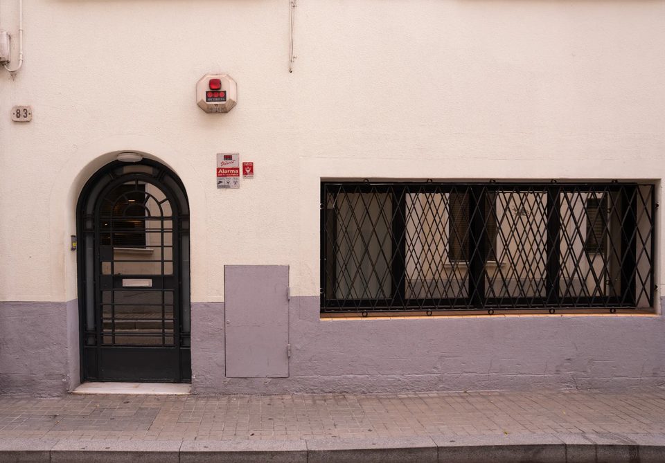 Fachada del Hotel Casita Amarilla en Calle Padua 83, Barcelona: puerta arqueada de forja y número 83